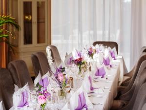 einen langen Tisch mit weißen Tischen und lila Blumen in der Unterkunft Central Hotel am Königshof in Viernheim