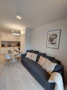 a living room with a blue couch and a kitchen at Harmony Pearl Apart in Rogowo