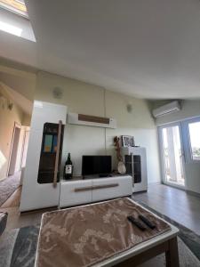 ein Wohnzimmer mit einem TV und einem Tisch in der Unterkunft Dvosoban kompletno sredjen stan in Tivat
