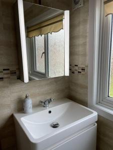 a bathroom with a white sink and a mirror at Cosy Daffodil Cottage in Eythorne