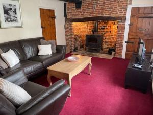 a living room with a couch and a table and a fireplace at Cosy Daffodil Cottage in Eythorne