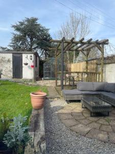 a garden with a couch and a wooden pergola at Cosy Daffodil Cottage in Eythorne