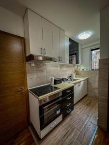 cocina con armarios blancos y fogones en Dado apartman 2 en Kraljevo