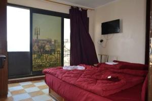 una camera con un letto rosso e una grande finestra di Al Waha Hostel a Il Cairo