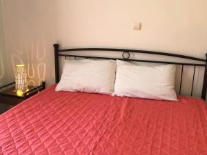 a bed with a red comforter and two white pillows at Ammodares in Lixouri