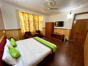 a hotel room with a bed and a television at Woodstock Inn Manali in Manāli