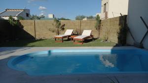 una piscina en un patio con 2 bancos en un patio trasero en EL BAGUAL DE MONTE en San Miguel del Monte