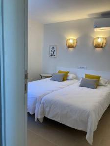 2 camas en un dormitorio con sábanas blancas y almohadas amarillas en Apartamento La Mimosa, en San Agustín