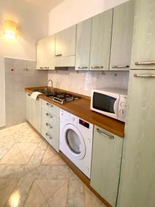 a kitchen with a washing machine and a microwave at Casa vacanza comoda con vista in Bosa