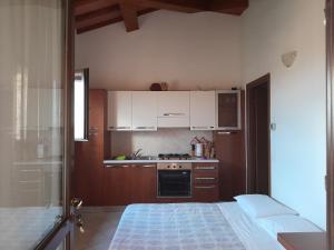 uma cozinha com armários brancos e uma cama num quarto em Finestra Della Val D'Orcia em Contignano
