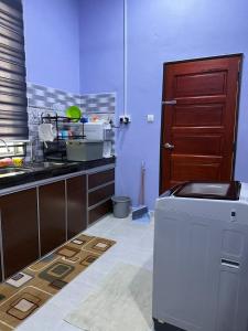 a kitchen with a sink and a refrigerator in it at Homestay Haji Noor in Tanah Merah