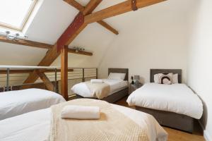 a room with three beds with white sheets at Cozy Downtown Loft in Bradford in Bradford
