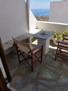 una mesa y sillas en un balcón con vistas al océano en ANATOLI ROOMS SERIFOS en Serifos
