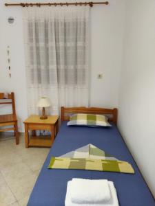 1 dormitorio con cama azul y ventana en ANATOLI ROOMS SERIFOS en Serifos