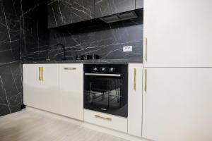 a kitchen with white cabinets and a black oven at Prime Apartments City Centre 48 in Suceava