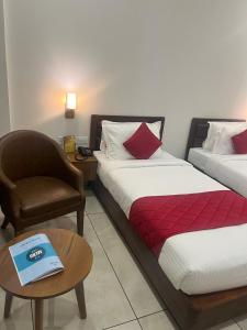 una camera d'albergo con due letti, una sedia e un tavolo di Hotel Abaam Neil ad Alleppey
