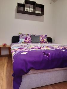 ein Bett mit einer lila Decke darüber in der Unterkunft Oficerski apartment in Bitola