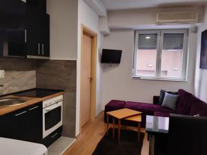 eine Küche und ein Wohnzimmer mit einem lila Sofa in der Unterkunft Oficerski apartment in Bitola