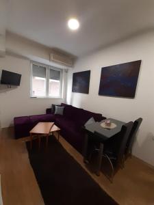 ein Wohnzimmer mit einem lila Sofa und einem Tisch in der Unterkunft Oficerski apartment in Bitola