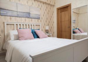 a bedroom with a white bed with pink and blue pillows at Torre Opus 31 - Apto.605 in Santo Domingo +23 photos