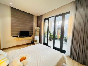 a bedroom with a large white bed and a television at Bibi’s home in Danang