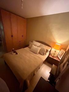 een slaapkamer met een bed en een tafel met een lamp bij A private room in a modern apartment near the Belinson/Schneider hospital and the Red Line to Tel Aviv in Petach Tikwa