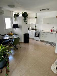 ペタフ・ティクヴァにあるA private room in a modern apartment near the Belinson/Schneider hospital and the Red Line to Tel Avivの広いキッチン(テーブル付)、白いキャビネット付きのキッチンが備わります。