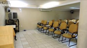 a room with rows of chairs and a tv at HOTEL PRINCIPE in Governador Valadares