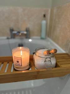 a candle sitting on a wooden tray in a bath tub at New Farm Cheshire B&B in Winsford