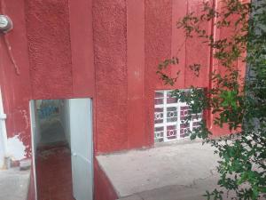 a red building with a door and a mirror at Alojamiento frente al foro de las estrellas para 5 personas 2 habitaciones compartidas baño independiente in Aguascalientes