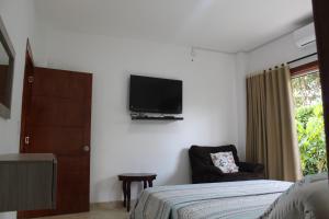 um quarto com uma cama e uma televisão na parede em Finca Hotel Casa Lupe En Santa Elena em El Cerrito