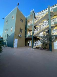 ein Apartmenthaus mit einer Treppe neben einem Parkplatz in der Unterkunft Samba Tako Plaza Home Suites in Sukuta