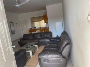 ein Wohnzimmer mit einem Ledersofa und einem Tisch in der Unterkunft Samba Tako Plaza Home Suites in Sukuta