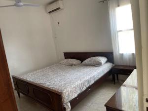 ein Schlafzimmer mit einem Bett und zwei Fenstern in der Unterkunft Samba Tako Plaza Home Suites in Sukuta