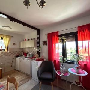 una cucina con tende rosse, tavolo e sedia di Dolina mira a Knić