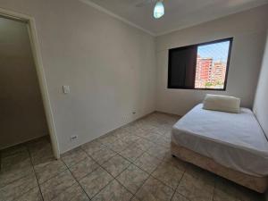 een slaapkamer met een bed en een flatscreen-tv bij Tupi Vista MAR III com VARANDA - 3 dormitórios - 50 metros da praia - com área de lazer PISCINA e salão de jogos - ESTACIONAMENTO gratuito in Praia Grande
