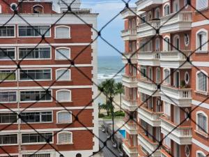 uitzicht op gebouwen van achter een hek bij Tupi Vista MAR III com VARANDA - 3 dormitórios - 50 metros da praia - com área de lazer PISCINA e salão de jogos - ESTACIONAMENTO gratuito in Praia Grande