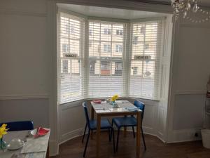 a dining room with a table and chairs and windows at Braemar in Weymouth