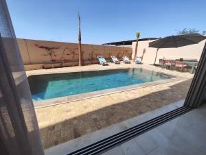 einen Pool mit 2 Stühlen und einem Sonnenschirm in der Unterkunft Villa Saadia in Douar Bellouk
