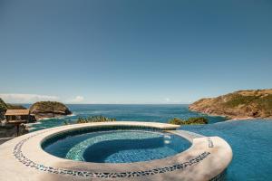 una piscina con el océano en el fondo en Cliffside Luxury Inn, en Búzios