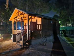 Cabaña pequeña con porche por la noche en Casa de madera en urbanización con gran piscina entre pinos, en Liria