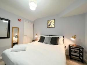a bedroom with a large white bed and a mirror at Suitely Stays Patio Apartment in Cheltenham