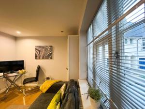 a living room with a couch and a large window at Suitely Stays Patio Apartment in Cheltenham