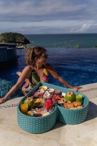 uma mulher ao lado de um tabuleiro de comida ao lado de uma piscina em Cliffside Luxury Inn em Búzios