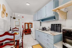 uma cozinha com armários brancos e uma mesa em MADA HOUSE's II em Sesimbra