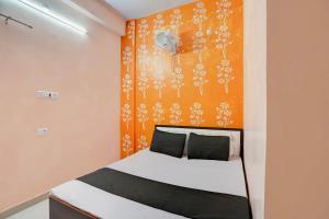 um quarto com uma cama com uma parede laranja em OYO Flagship Hotel Divy inn em Prayagraj