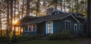 ein kleines Haus mit der Sonne, die durch die Bäume scheint in der Unterkunft White Pine Camp in Paul Smiths