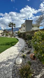 une passerelle en pierre menant à une maison avec un palmier dans l'établissement Garni Hotello Sport And Relax, à Riva del Garda