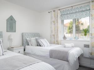 two beds in a white bedroom with a window at 14 Belvedere Court in Paignton