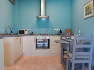 a kitchen with white cabinets and a blue wall at Ty Ffair Mai Annexe in Llangwm-isaf